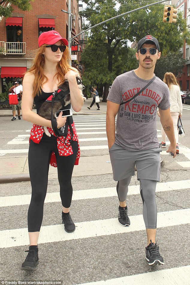 What a beauty: The alabaster skinned beauty continued her all black ensemble with a pair stylish trainers as she covered her loose flame-haired tresses with a vibrant red Mickey Mouse hat