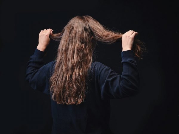 Девушка держит в руках две равные части волос на голове