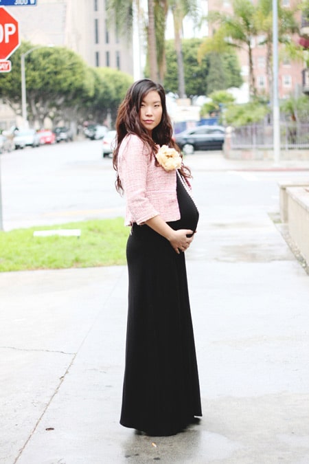 Беременная девушка в длинном черном платье и нежно розовом жакете