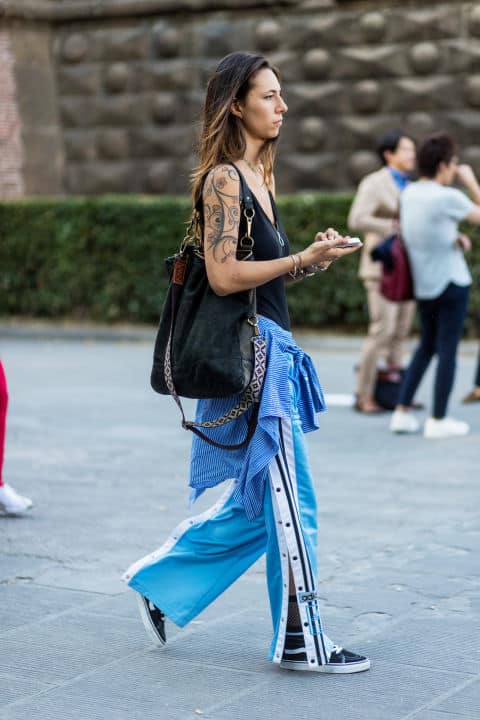 Девушка в голубых штанах, черный топ и большая сумка
