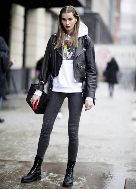 Девушка в серых скинни, белая худи, ботинки на шнуровке и куртка косуха