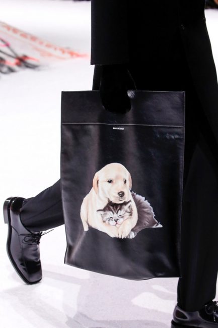Черный total-look разбавляет черная сумка со щенками 